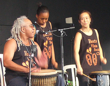 Three of the drummers performing, some using hands and others drumsticks
