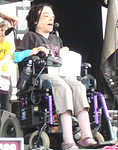 Picture of Liz Carr on stage in her wheelchair. She has quite a sharp and sarcastic sense of humour